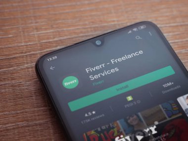 Lod, Israel - 8 Temmuz 2020: Fiverr uygulama oyun mağazası sayfası ahşap arka planda siyah bir cep telefonu ekranında. Üst görünüm düzlüğü kopyalama alanı ile yatıyordu.