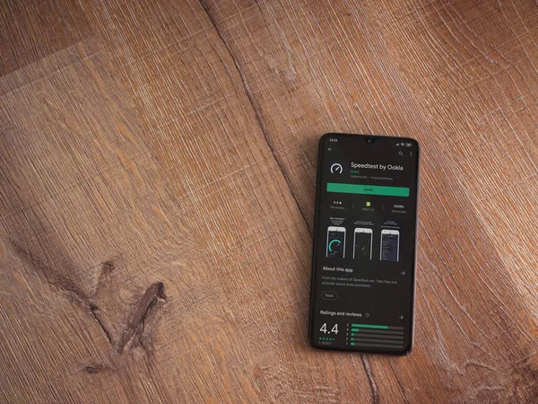 Lod, Israel - 8 Temmuz 2020: Ahşap arka planda siyah bir cep telefonunun ekranında en hızlı uygulama oyun mağazası sayfası. Üst görünüm düzlüğü kopyalama alanı ile yatıyordu.