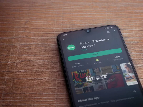 Lod, Israel - 8 Temmuz 2020: Fiverr uygulama oyun mağazası sayfası ahşap arka planda siyah bir cep telefonu ekranında. Üst görünüm düzlüğü kopyalama alanı ile yatıyordu.