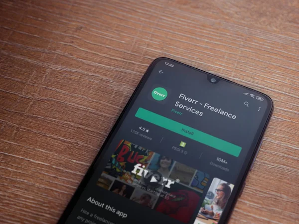 Lod, Israel - 8 Temmuz 2020: Fiverr uygulama oyun mağazası sayfası ahşap arka planda siyah bir cep telefonu ekranında. Üst görünüm düzlüğü kopyalama alanı ile yatıyordu.
