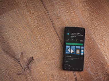 Lod, Israel - 8 Temmuz 2020: Faks Plus uygulama oyun mağazası sayfası ahşap arka planda siyah bir cep telefonunun ekranında. Üst görünüm düzlüğü kopyalama alanı ile yatıyordu.