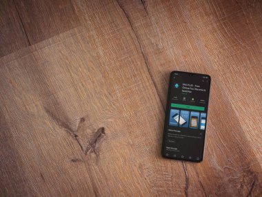 Lod, Israel - 8 Temmuz 2020: Faks Plus uygulama oyun mağazası sayfası ahşap arka planda siyah bir cep telefonunun ekranında. Üst görünüm düzlüğü kopyalama alanı ile yatıyordu.