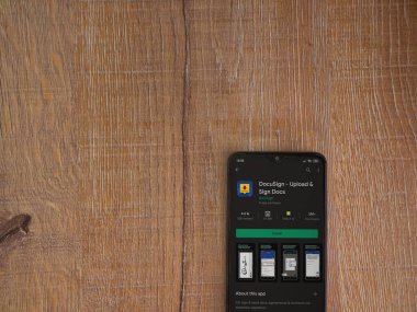 Lod, Israel - 8 Temmuz 2020: Docusign uygulama oyun mağazası sayfası ahşap arka planda siyah bir cep telefonunun ekranında. Üst görünüm düzlüğü kopyalama alanı ile yatıyordu.