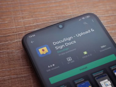 Lod, Israel - 8 Temmuz 2020: Docusign uygulama oyun mağazası sayfası ahşap arka planda siyah bir cep telefonunun ekranında. Üst görünüm düzlüğü kopyalama alanı ile yatıyordu.