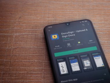 Lod, Israel - 8 Temmuz 2020: Docusign uygulama oyun mağazası sayfası ahşap arka planda siyah bir cep telefonunun ekranında. Üst görünüm düzlüğü kopyalama alanı ile yatıyordu.