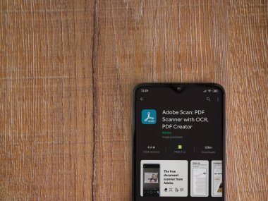Lod, Israel - 8 Temmuz 2020: Adobe Scan uygulaması oyun mağazası sayfası ahşap arka planda siyah bir cep telefonu ekranında. Üst görünüm düzlüğü kopyalama alanı ile yatıyordu.