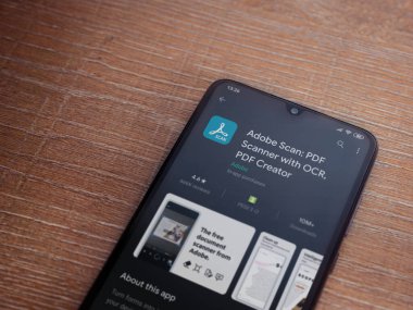 Lod, Israel - 8 Temmuz 2020: Adobe Scan uygulaması oyun mağazası sayfası ahşap arka planda siyah bir cep telefonu ekranında. Üst görünüm düzlüğü kopyalama alanı ile yatıyordu.