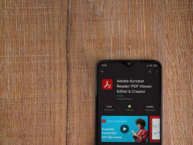 Lod, Israel - 8 Temmuz 2020: Adobe Acrobat Reader uygulama oyun mağazası sayfası ahşap arka planda siyah bir cep telefonu sergilenmektedir. Üst görünüm düzlüğü kopyalama alanı ile yatıyordu.