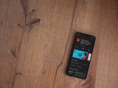 Lod, Israel - 8 Temmuz 2020: Adobe Acrobat Reader uygulama oyun mağazası sayfası ahşap arka planda siyah bir cep telefonu sergilenmektedir. Üst görünüm düzlüğü kopyalama alanı ile yatıyordu.