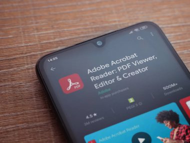 Lod, Israel - 8 Temmuz 2020: Adobe Acrobat Reader uygulama oyun mağazası sayfası ahşap arka planda siyah bir cep telefonu sergilenmektedir. Üst görünüm düzlüğü kopyalama alanı ile yatıyordu.