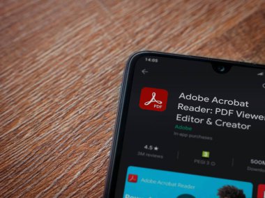 Lod, Israel - 8 Temmuz 2020: Adobe Acrobat Reader uygulama oyun mağazası sayfası ahşap arka planda siyah bir cep telefonu sergilenmektedir. Üst görünüm düzlüğü kopyalama alanı ile yatıyordu.