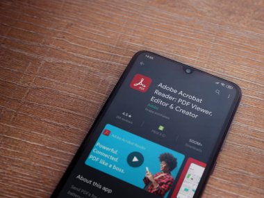Lod, Israel - 8 Temmuz 2020: Adobe Acrobat Reader uygulama oyun mağazası sayfası ahşap arka planda siyah bir cep telefonu sergilenmektedir. Üst görünüm düzlüğü kopyalama alanı ile yatıyordu.