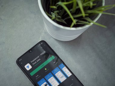 Lod, Israel - 8 Temmuz 2020: Mermer arka planda Freelancer uygulaması oyun mağazası sayfası olan siyah cep telefonlu modern minimalist ofis çalışma alanı. Üst görünüm düzlüğü kopyalama alanı ile yatıyordu.