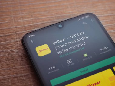 Lod, Israel - 8 Temmuz 2020: Sarı uygulama oyun mağazası sayfası ahşap arka planda siyah bir cep telefonunun ekranında. Üst görünüm düzlüğü kopyalama alanı ile yatıyordu.