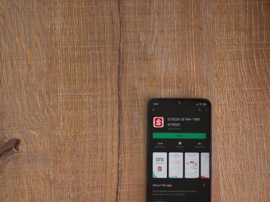 Lod, Israel - 8 Temmuz 2020: Süper Pharm uygulama oyun mağazası sayfası ahşap arka planda siyah bir cep telefonunun ekranında. Üst görünüm düzlüğü kopyalama alanı ile yatıyordu.