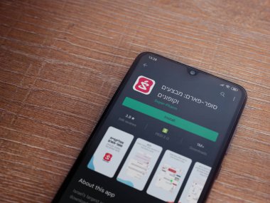 Lod, Israel - 8 Temmuz 2020: Süper Pharm uygulama oyun mağazası sayfası ahşap arka planda siyah bir cep telefonunun ekranında. Üst görünüm düzlüğü kopyalama alanı ile yatıyordu.