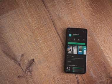 Lod, Israel - 8 Temmuz 2020: Ahşap arka planda siyah bir cep telefonunun ekranında uygulamalı oyun mağazası sayfasını tara. Üst görünüm düzlüğü kopyalama alanı ile yatıyordu.