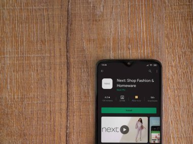 Lod, Israel - 8 Temmuz 2020: Sonraki uygulama oyun mağazası sayfası ahşap arka planda siyah bir cep telefonunun ekranında. Üst görünüm düzlüğü kopyalama alanı ile yatıyordu.