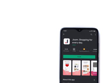 Lod, Israel - 8 Temmuz 2020: Beyaz arka planda izole edilmiş siyah bir cep telefonunun ekranında Joom uygulaması oyun mağazası sayfası. Üst görünüm düzlüğü kopyalama alanı ile yatıyordu.