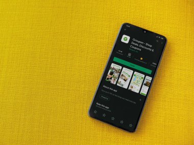 Lod, Israel - 8 Temmuz 2020: Groupon uygulaması oyun mağazası sayfası sarı kumaş arka planda siyah bir cep telefonunun ekranında. Üst görünüm düzlüğü kopyalama alanı ile yatıyordu.