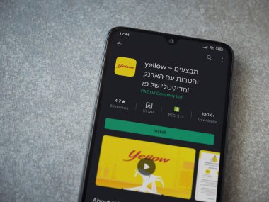 Lod, Israel - 8 Temmuz 2020: Sarı uygulama oyun mağazası sayfası seramik taş zemin üzerinde siyah bir cep telefonunun görüntüsü. Üst görünüm düzlüğü kopyalama alanı ile yatıyordu.