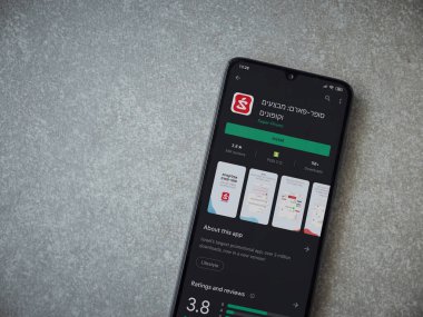 Lod, Israel - 8 Temmuz 2020: Seramik taş zemin üzerinde siyah bir cep telefonunun sergilendiği Super Pharm uygulaması oyun mağazası sayfası. Üst görünüm düzlüğü kopyalama alanı ile yatıyordu.