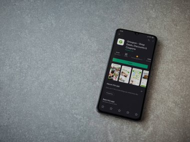 Lod, Israel - 8 Temmuz 2020: Groupon uygulaması oyun mağazası sayfası seramik taş zemin üzerinde siyah bir cep telefonu görüntüsü. Üst görünüm düzlüğü kopyalama alanı ile yatıyordu.