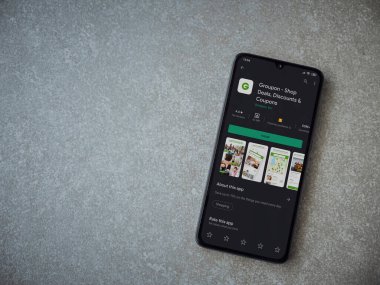 Lod, Israel - 8 Temmuz 2020: Groupon uygulaması oyun mağazası sayfası seramik taş zemin üzerinde siyah bir cep telefonu görüntüsü. Üst görünüm düzlüğü kopyalama alanı ile yatıyordu.