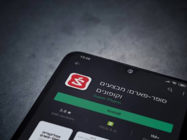 Lod, Israel - 8 Temmuz 2020: Süper Pharm uygulama oyun mağazası sayfası koyu mermer taştan arka planda siyah bir cep telefonunun ekranında. Üst görünüm düzlüğü kopyalama alanı ile yatıyordu.