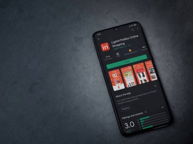 Lod, Israil - 8 Temmuz 2020: Koyu mermer taştan arka planda siyah bir cep telefonunun ekranında uygulamalı oyun mağazası sayfası aydınlanıyor. Üst görünüm düzlüğü kopyalama alanı ile yatıyordu.