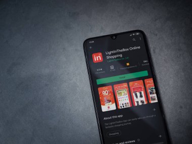 Lod, Israil - 8 Temmuz 2020: Koyu mermer taştan arka planda siyah bir cep telefonunun ekranında uygulamalı oyun mağazası sayfası aydınlanıyor. Üst görünüm düzlüğü kopyalama alanı ile yatıyordu.