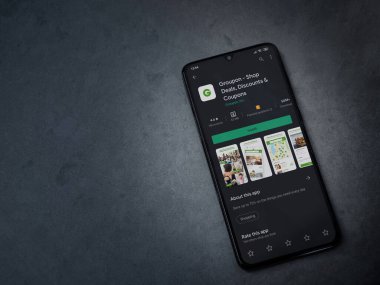 Lod, Israel - 8 Temmuz 2020: Groupon uygulaması oyun mağazası sayfası koyu mermer taştan arka planda siyah bir cep telefonunun ekranında. Üst görünüm düzlüğü kopyalama alanı ile yatıyordu.