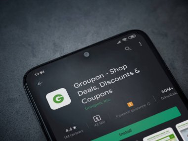 Lod, Israel - 8 Temmuz 2020: Groupon uygulaması oyun mağazası sayfası koyu mermer taştan arka planda siyah bir cep telefonunun ekranında. Üst görünüm düzlüğü kopyalama alanı ile yatıyordu.