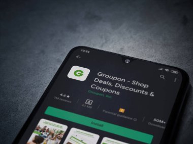 Lod, Israel - 8 Temmuz 2020: Groupon uygulaması oyun mağazası sayfası koyu mermer taştan arka planda siyah bir cep telefonunun ekranında. Üst görünüm düzlüğü kopyalama alanı ile yatıyordu.