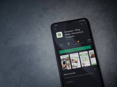 Lod, Israel - 8 Temmuz 2020: Groupon uygulaması oyun mağazası sayfası koyu mermer taştan arka planda siyah bir cep telefonunun ekranında. Üst görünüm düzlüğü kopyalama alanı ile yatıyordu.