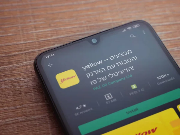 Lod, Israel - 8 Temmuz 2020: Sarı uygulama oyun mağazası sayfası ahşap arka planda siyah bir cep telefonunun ekranında. Üst görünüm düzlüğü kopyalama alanı ile yatıyordu.