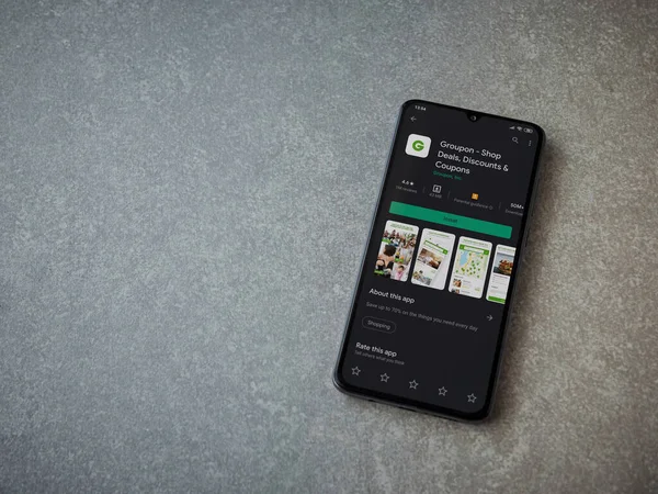 Lod, Israel - 8 Temmuz 2020: Groupon uygulaması oyun mağazası sayfası seramik taş zemin üzerinde siyah bir cep telefonu görüntüsü. Üst görünüm düzlüğü kopyalama alanı ile yatıyordu.