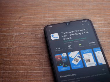 Lod, Israel - 8 Temmuz 2020: Truecaller uygulama oyun mağazası sayfası ahşap arka planda siyah bir cep telefonunun ekranında. Üst görünüm düzlüğü kopyalama alanı ile yatıyordu.