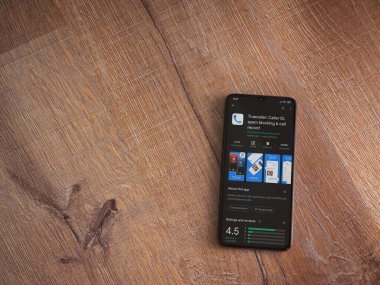 Lod, Israel - 8 Temmuz 2020: Truecaller uygulama oyun mağazası sayfası ahşap arka planda siyah bir cep telefonunun ekranında. Üst görünüm düzlüğü kopyalama alanı ile yatıyordu.
