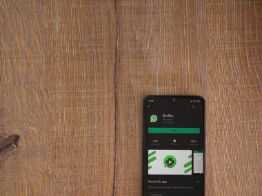 Lod, Israel - 8 Temmuz 2020: Scriby uygulama oyun mağazası sayfası ahşap arka planda siyah bir cep telefonunun ekranında. Üst görünüm düzlüğü kopyalama alanı ile yatıyordu.