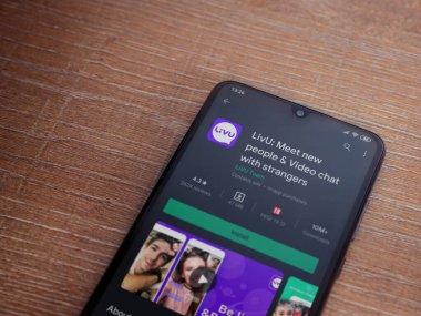 Lod, Israel - 8 Temmuz 2020: LiveU uygulama oyun mağazası sayfası ahşap arka planda siyah bir cep telefonu ekranında. Üst görünüm düzlüğü kopyalama alanı ile yatıyordu.