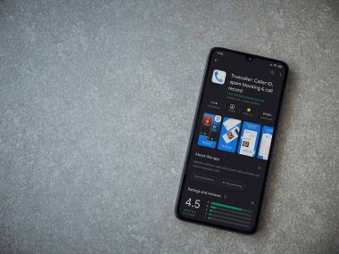 Lod, Israel - 8 Temmuz 2020: Truecaller uygulaması oyun mağazası sayfası seramik taş zemin üzerinde siyah bir cep telefonu görüntüsü. Üst görünüm düzlüğü kopyalama alanı ile yatıyordu.