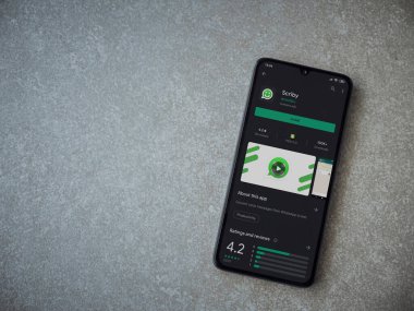 Lod, Israel - 8 Temmuz 2020: Scriby uygulama oyun mağazası sayfası seramik taş zemin üzerinde siyah bir cep telefonu görüntüsü. Üst görünüm düzlüğü kopyalama alanı ile yatıyordu.