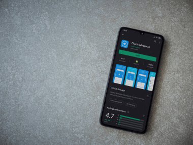 Lod, Israel - 8 Temmuz 2020: Hızlı Mesaj uygulaması oyun mağazası sayfası seramik taş zemin üzerinde siyah bir cep telefonu görüntüsü. Üst görünüm düzlüğü kopyalama alanı ile yatıyordu.