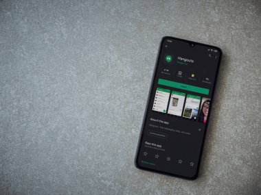 Lod, Israel - 8 Temmuz 2020: Hanghouts uygulaması oyun mağazası sayfası seramik taş zemin üzerinde siyah bir cep telefonu görüntüsü. Üst görünüm düzlüğü kopyalama alanı ile yatıyordu.