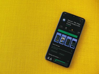 Lod, Israel - 8 Temmuz 2020: Sarı kumaş arka planda siyah bir cep telefonu ekranında Discord uygulaması oyun mağazası sayfası. Üst görünüm düzlüğü kopyalama alanı ile yatıyordu.