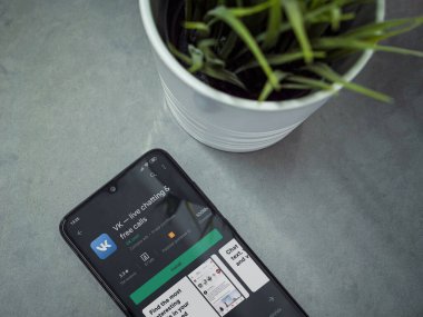 Lod, Israel - 8 Temmuz 2020: Mermer arka planda VK uygulama oyun mağazası sayfası olan siyah cep telefonlu modern minimalist ofis çalışma alanı. Üst görünüm düzlüğü kopyalama alanı ile yatıyordu.