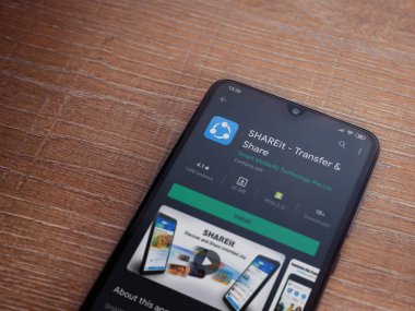 Lod, Israel - 8 Temmuz 2020: SharEit uygulaması oyun mağazası sayfası ahşap arka planda siyah bir cep telefonunun ekranında. Üst görünüm düzlüğü kopyalama alanı ile yatıyordu.