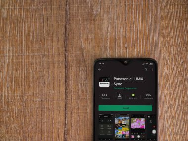 Lod, Israel - 8 Temmuz 2020: Panasonic LUMIX Sync uygulama oyun mağazası sayfası ahşap arka planda siyah bir cep telefonu görüntüsü. Üst görünüm düzlüğü kopyalama alanı ile yatıyordu.