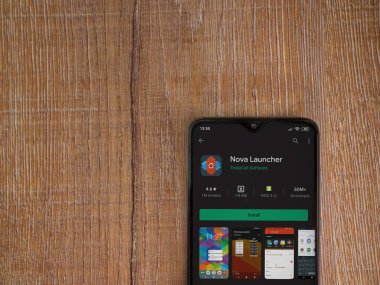 Lod, Israel - 8 Temmuz 2020: Nova Launcher uygulaması oyun mağazası sayfası ahşap arka planda siyah bir cep telefonu ekranında. Üst görünüm düzlüğü kopyalama alanı ile yatıyordu.